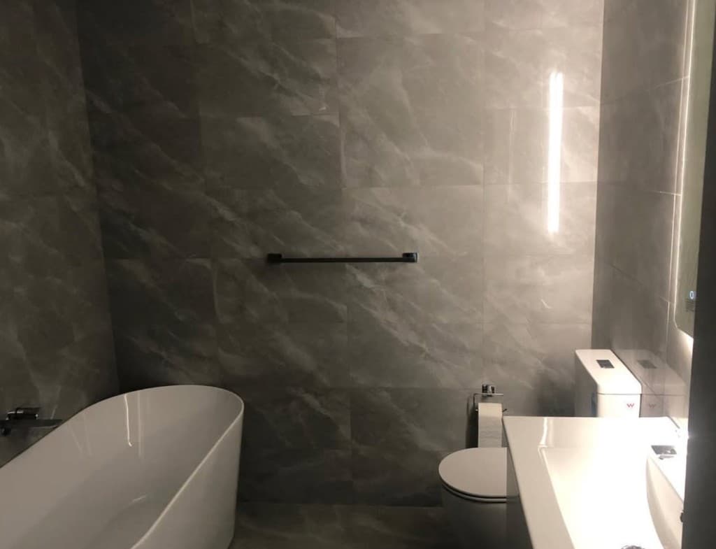 Grey marble ensuite with freestanding bath and backlit mirror